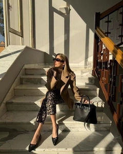 Détail d'un blazer camel et d'un pantalon léopard sur un escalier en marbre