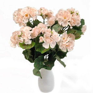 Detail of faux light pink geraniums with green leaves in a white vase decoration