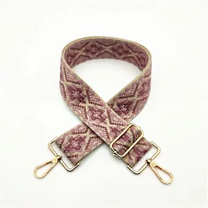 Close-up of wide bohemian geometric woven purse strap with gold adjustable metal hardware