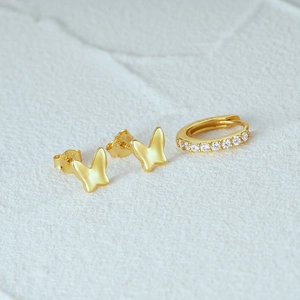 Macro shot of S925 gold-plated butterfly studs and a sparkling zircon-set hoop earring