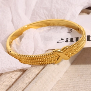 Macro view of 18K gold-plated stainless steel bangle with scale texture and X design