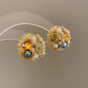 Macro detail of retro gold earrings with pearls, crystals and a vintage rose motif