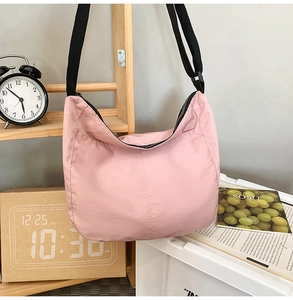 Detail of pink nylon dumpling crossbody bag showing textured fabric and crescent shape