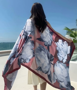 Detail of ethnic floral print sun protection shawl showing silk texture against sea background