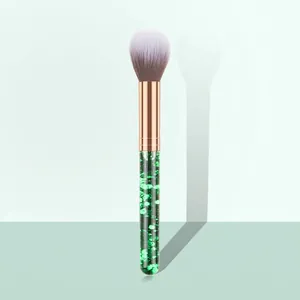 Macro detail of powder brush featuring green sequin handle and rose gold metal ferrule