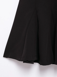 Detailed close-up showing the pleated texture and fabric of the black off-shoulder dress