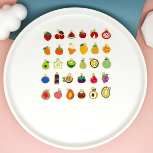Flat lay of colorful assorted mini enamel fruit pendants displayed on a round plate
