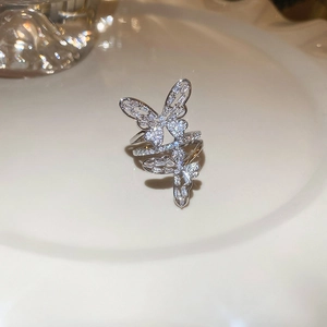 Macro view of double butterfly ring with sparkling zircon inlays on a beige tray