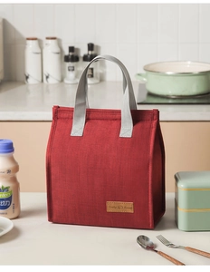 Red insulated lunch bag with Tasty Food leather patch in a modern kitchen setting
