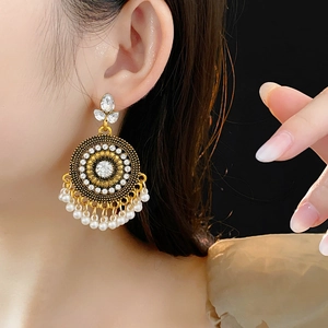 Dettaglio di orecchini jhumka vintage dorati con strass e nappe di perle bianche