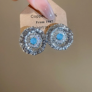Macro detail of silver flower earrings with sky blue zircon stones and metal petals