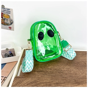 Detail view of green transparent PVC crossbody bag with patterned strap on wooden surface