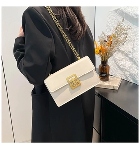 Détail d'un sac à bandoulière blanc crème avec fermoir doré et bandoulière chaîne