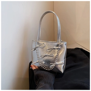 Close-up of silver handbag featuring 3D bow accents and elegant metallic bead chains