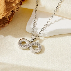 Macro shot of silver infinity necklace with crystals on white stone surface