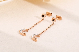 Detail of rose gold star and moon tassel earrings with white rhinestones and black inlay