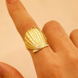 Detailed close-up of a golden shell shaped irregular open ring on a female finger