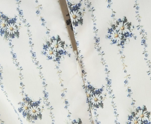 Detail view of white blue floral fabric with daisy stripes and hidden zipper