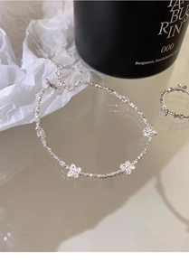 Dettaglio del bracciale a farfalla in argento e anello coordinato su superficie riflettente