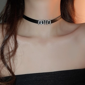 Gros plan du ras-de-cou en similicuir avec pendentif lettre miu serti de strass