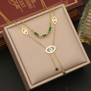 Detail of gold double-layer necklace with emerald stones and evil eye pendant on jewelry box