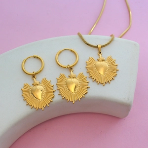 Parure de bijoux cœur sacré doré avec collier et boucles d'oreilles sur socle blanc