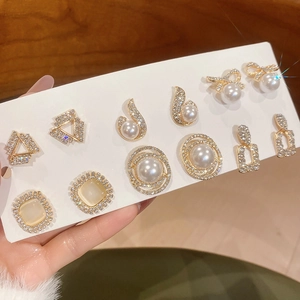 Macro shot of gold earring set featuring faux pearls, opal stones, and cubic zirconia studs