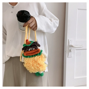 Close-up of yellow handmade knitted bag with sausage lips and large eyes decoration