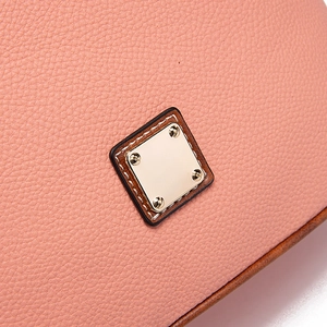 Detail of lychee textured leather crossbody bag with golden metal plate and fine stitching
