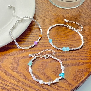 Three colorful beaded silver-tone bracelets with charms on a dark wood background
