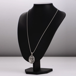 Oval silver stainless steel religious pendant necklace displayed on a black mannequin