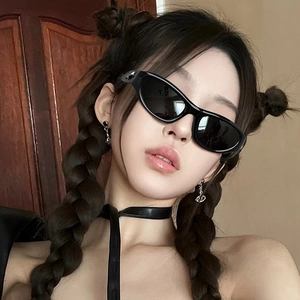 Close-up of trendy Y2K black oval sunglasses with stylish planet pendant earrings