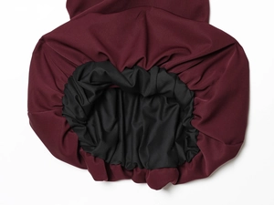Detail of burgundy balloon dress with elastic hem and contrasting black lining