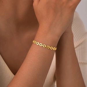 Close-up of gold-plated tank chain bracelet with polished H-shaped links on a model's wrist