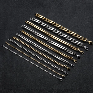 Professional display of gold and silver Cuban link chains with lobster clasps on black background