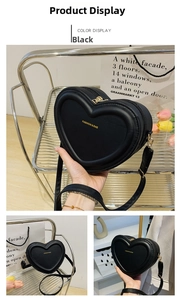 Détail du sac bandoulière noir en forme de cœur avec lettrage doré et finitions chic