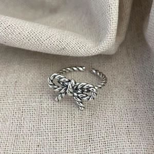 Detailed close-up of a vintage twisted silver bowknot ring on rustic linen fabric