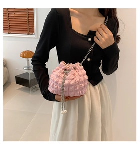 Pink pleated bucket bag with silver chain strap and pearl accents on a model