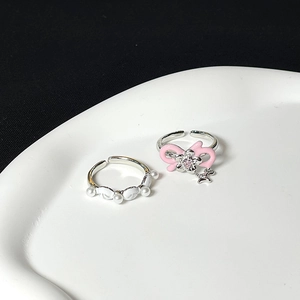 Detail of pink bow ring with crystal and white faux pearl open ring set on ceramic tray