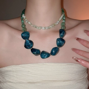 Close-up of double-layered necklace with green stone beads and blue marble pendants