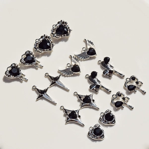 Detailed view of silver heart and cross pendants with black gemstones for jewelry making