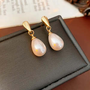 Detailed close-up of French vintage gold and teardrop pearl earrings on a black jewelry box