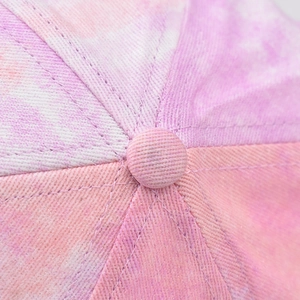 Macro detail of tie-dye baseball cap top button and premium twill fabric texture