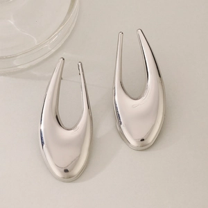 Macro detail of silver U-shaped metal earrings with a polished mirror finish and smooth curves