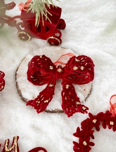 Détail du nœud de Noël floqué bordeaux avec motifs pailletés dorés sur base bois