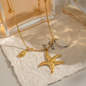 Golden sea style necklace featuring starfish, seashell and conch charms on a bead chain