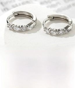 Detail of silver hoop earrings featuring marquise and round cubic zirconia in copper setting
