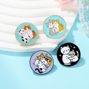 Set of four colorful round enamel cat pins with gold metal trim on a white display stand