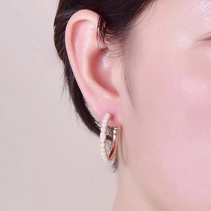 Close-up of gold-plated hoop earrings with elegant white pearls on a female model