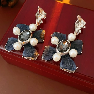 Macro detail of vintage floral earrings with blue petals and white pearls on jewelry box
